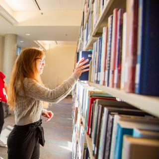 A student puts a book back on a library shelf