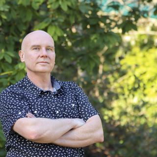 Dr. Chris Gill stands in a forested area at VIU's Nanaimo campus.