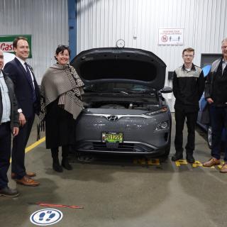 Five people pose around an electric vehicle