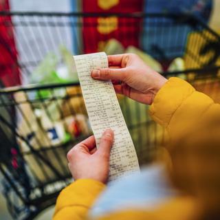 Hands hold a long bill with a grocery cart in the background