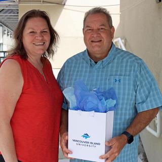 John with his wife Jen showing off the graduation gift he was given through the tuition waiver program