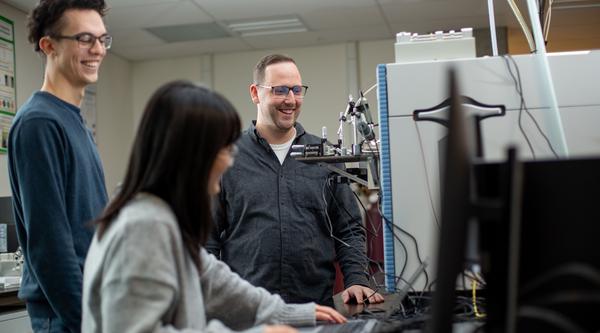 three people stand around a mass spectrometer