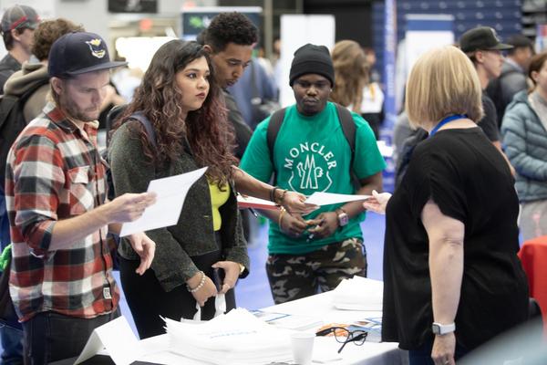 Three students interact with a vendor at the Career Fair