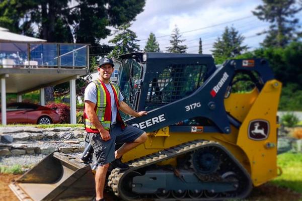 Jesse Anderson standing outside in front of one of his machines on a sunny day.