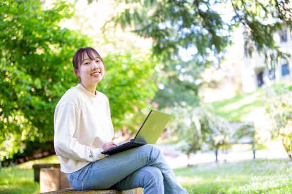 Student working on a laptop in nature