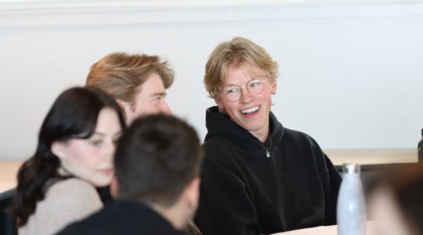 Group of students interacts while sitting at a table