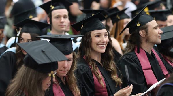 A group of graduates smile and listen to speeches