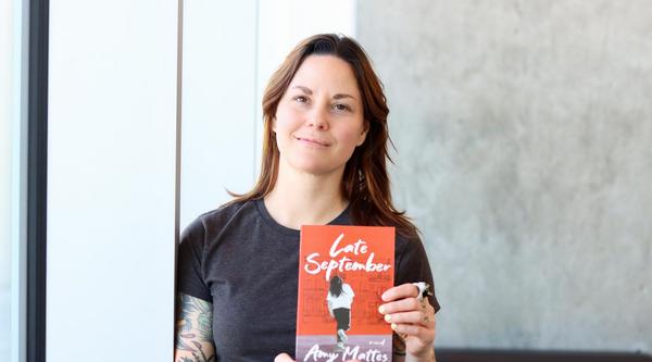 Amy Mattes holds up a copy of her book, Late September.