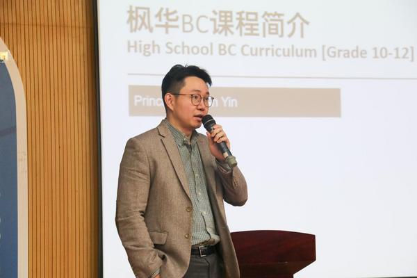 Brian Yin holds a microphone near a podium.