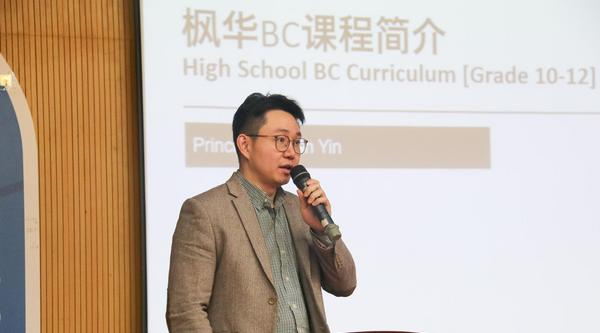 Brian Yin holds a microphone near a podium.