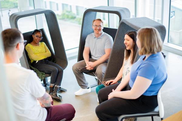 A group of students sits in cool chairs talking with each other