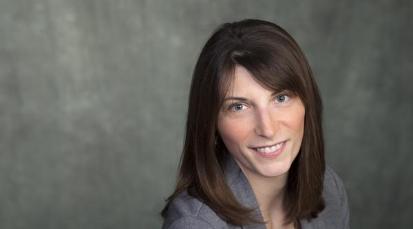 Headshot of Dr. Lindsay McCunn, wearing a grey blazer and smiling.