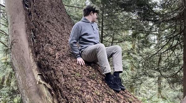 Ethan Hummel sits on a tree trunk.