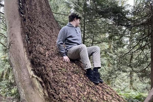 Ethan Hummel sits on a tree trunk.