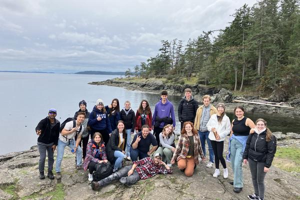 Group photo with a view of the ocean and trees behind them