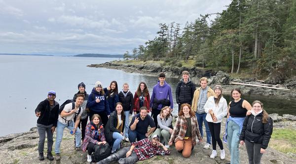 Group photo with a view of the ocean and trees behind them