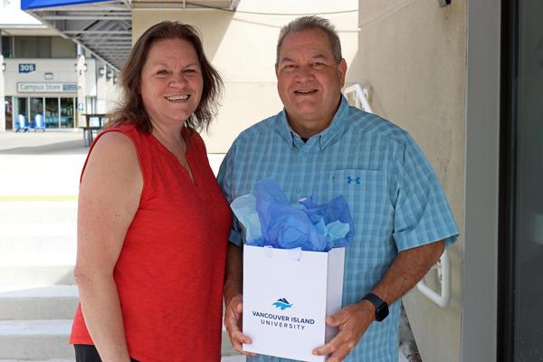 John with his wife Jen showing off the graduation gift he was given through the tuition waiver program