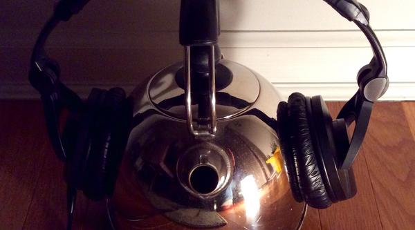 Headphones resting on a tea kettle.