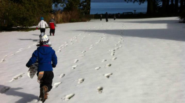 Children running across a snowy lawn