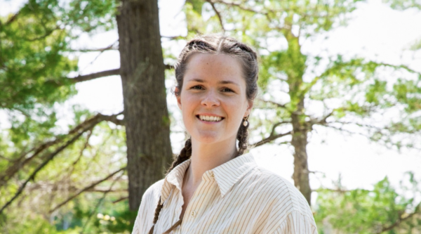 Laura Hutchinson smiling at the camera with trees in the background.