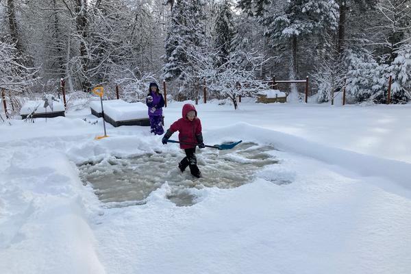 Children on a rink clearing the snow off