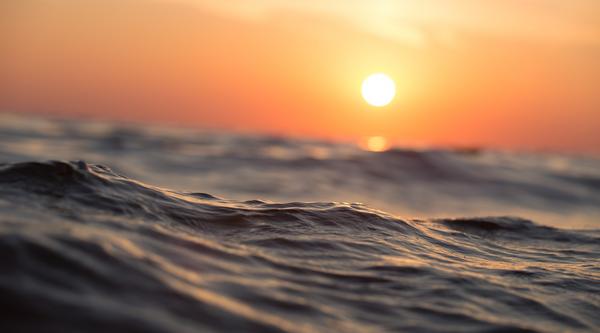 An orange and yellow sunset above ocean waves.