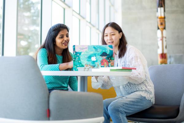 Two women look at a laptop screen together