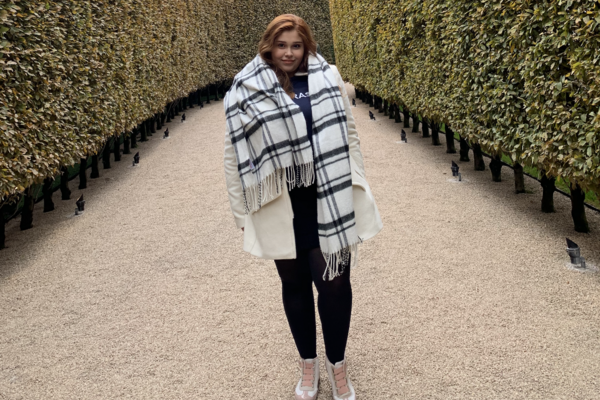 Gabrielle Hayashi Santos standing outside between two hedges looking at the camera 