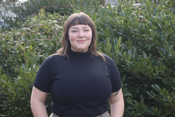 Sierra De Buysscher-Nailor standing smiling at the camera in front of a bush