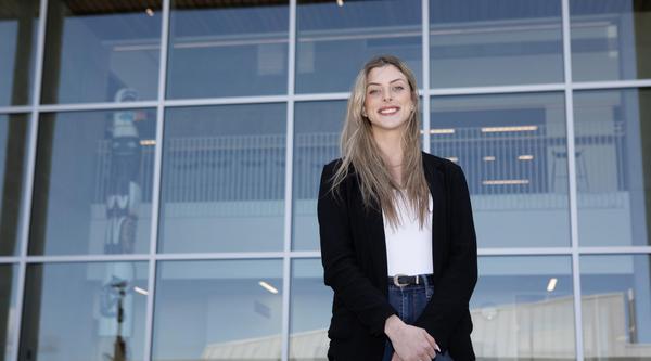 Teagan stands outside the glass windows on the Centre for Health and Science at VIU's Nanaimo campus