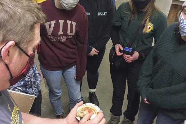 VIU students examine a scallop held by Provan Crump, from Coastal Shellfish Ltd.