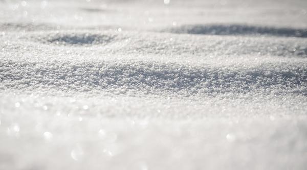 A closeup of snow with the sun shining on it.