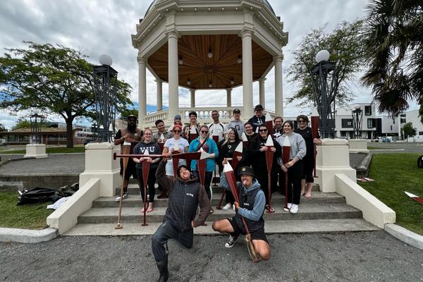 a group holding paddles poses for a photo