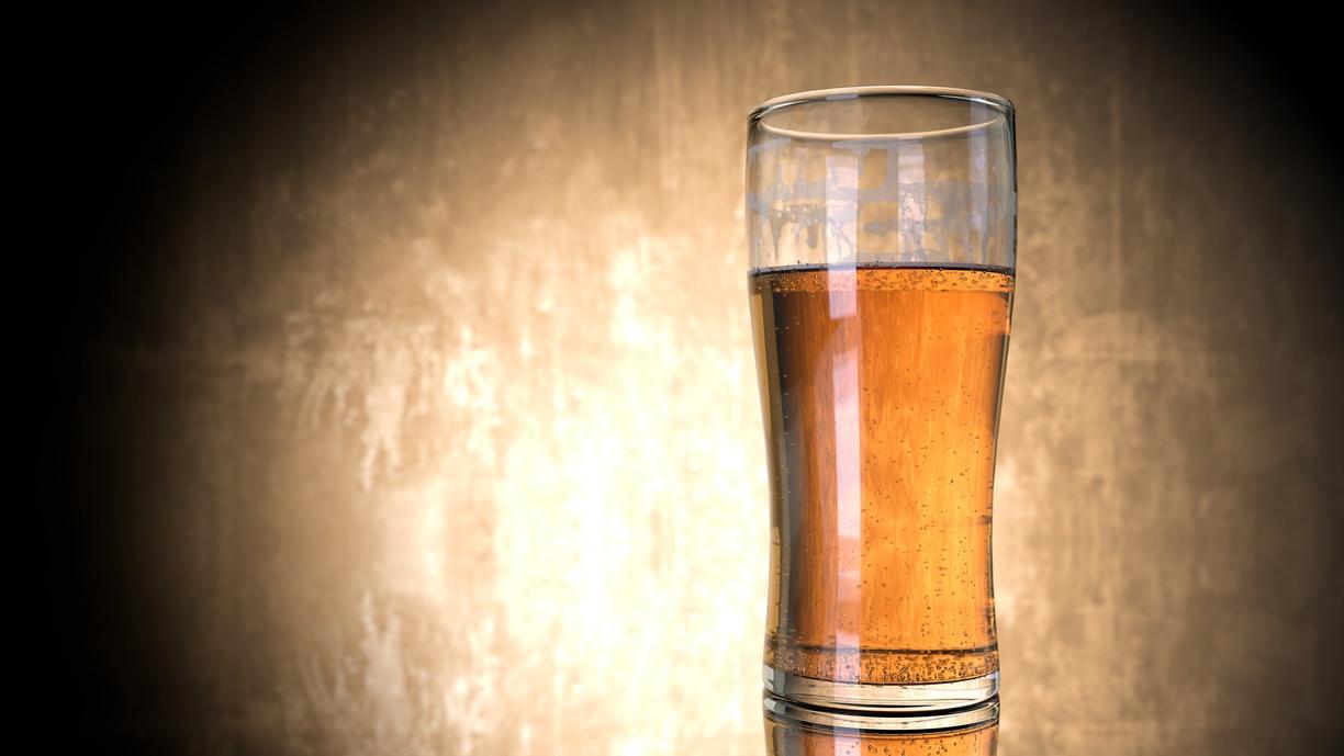 A glass of beer on a table in front of a tan an black background. Image featured in Dr. Marie Hopwood, VIU Department of Anthropology, Archaeology Beer blog