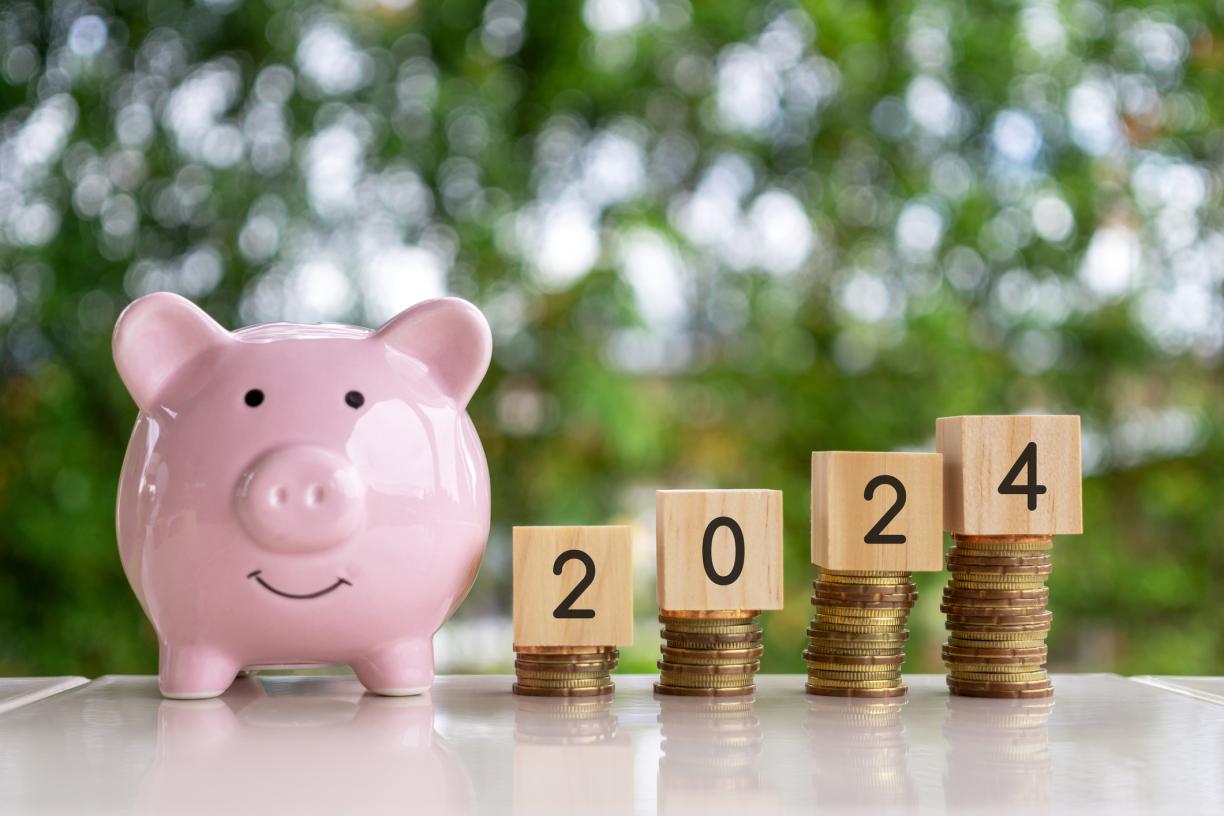 piggy bank with coins stacked next to it, blocks on top that read 2024