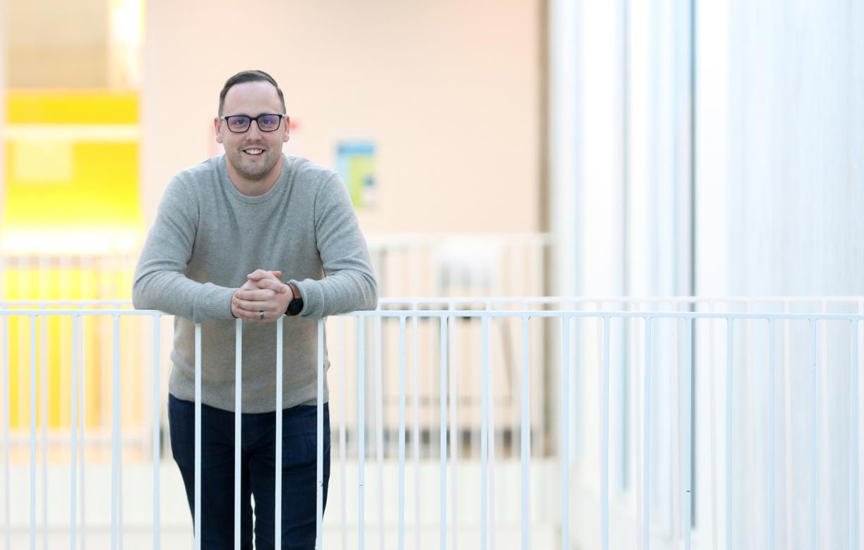 Dr. Kyle Duncan, a VIU Chemistry Professor,  smiles while leaning against a white railing.