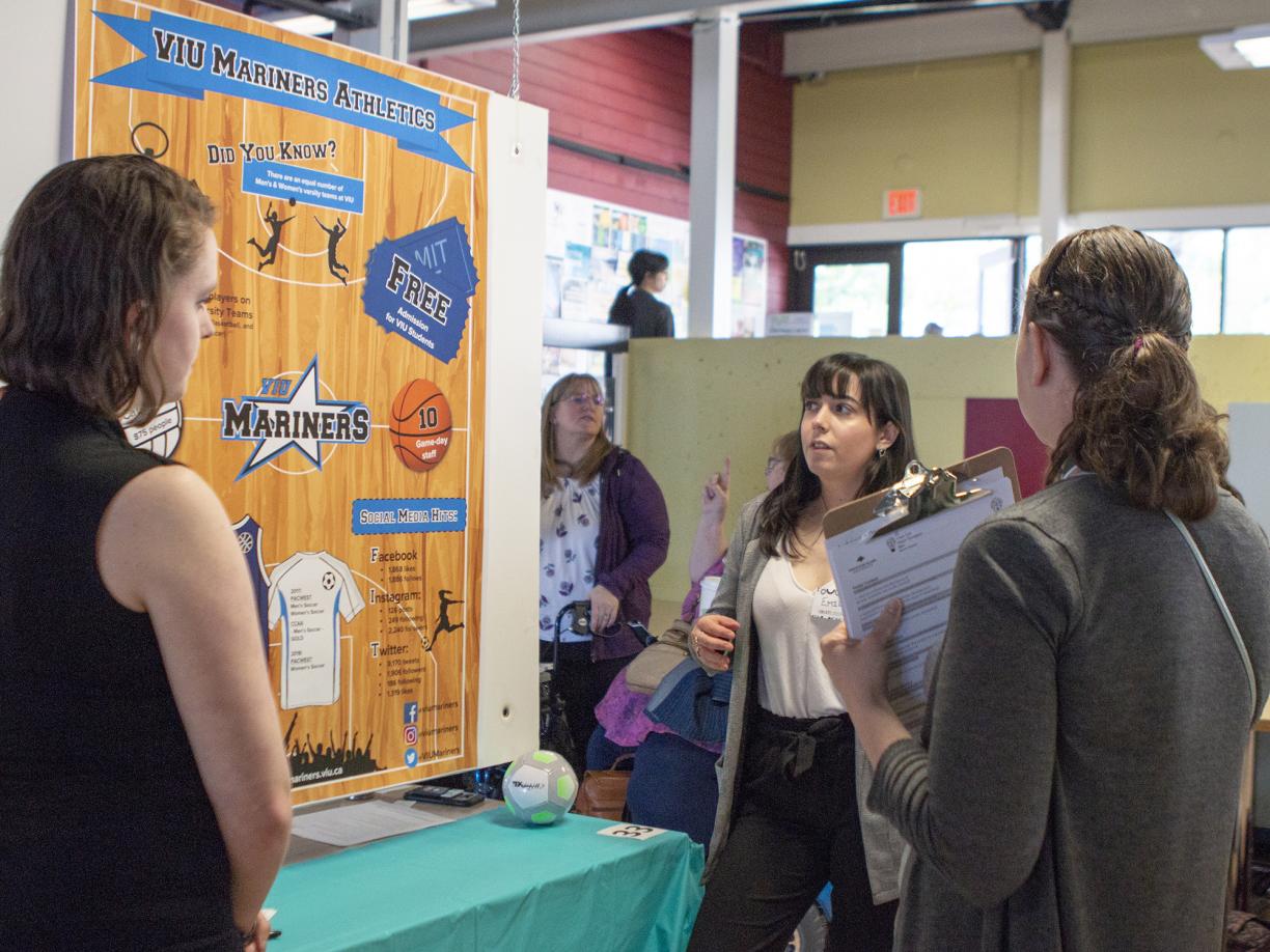 Three students examine a research poster at CREATE.