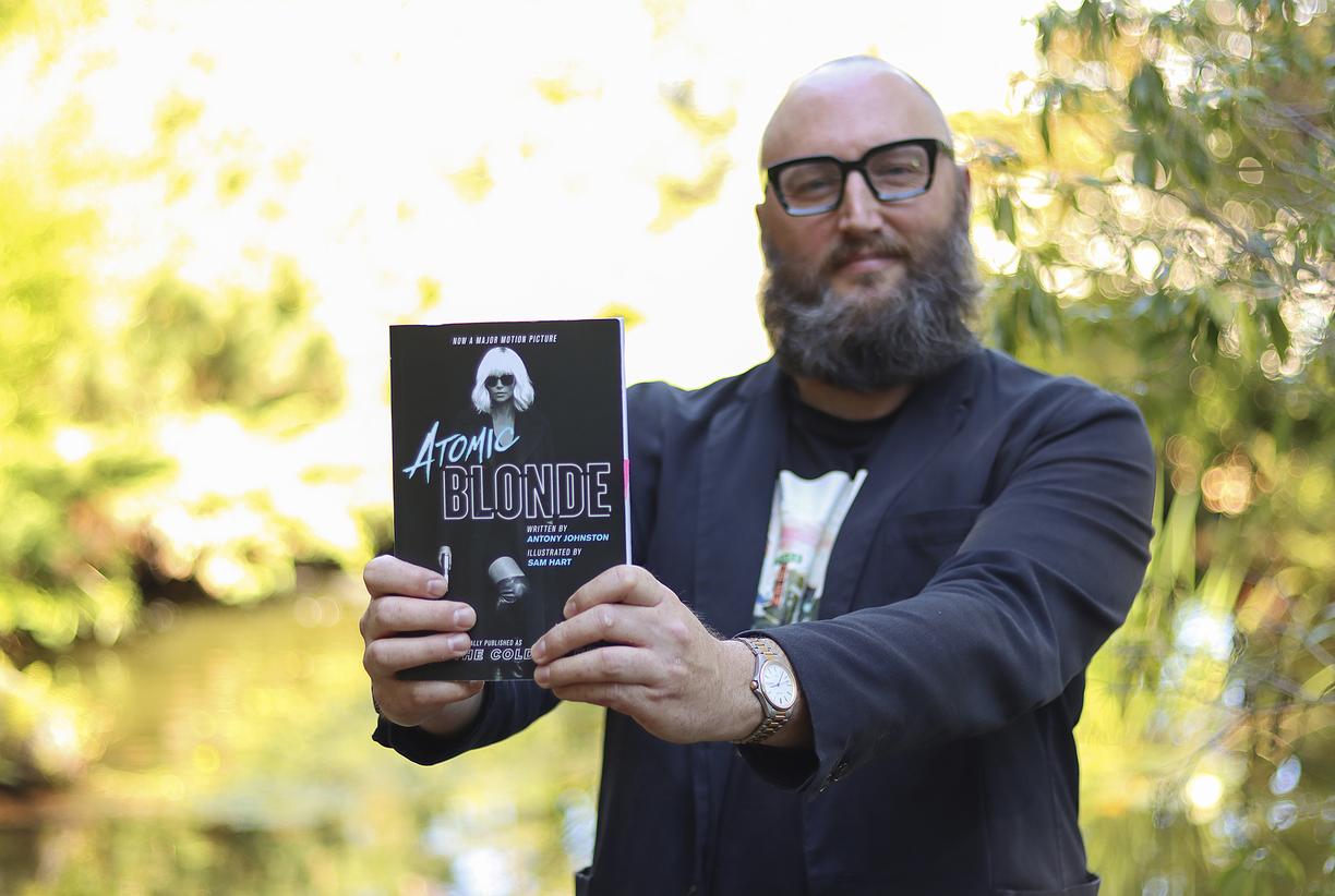 Theo Finigan holds out a copy of the book Atomic Blonde 