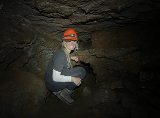 Aiden Kilcommons wears an orange hardhat while exploring a cave.